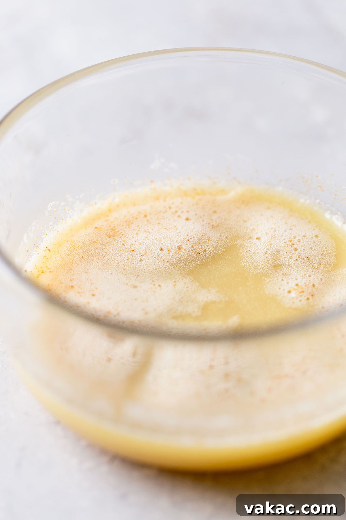 A glass mixing bowl holding cooled browned butter.