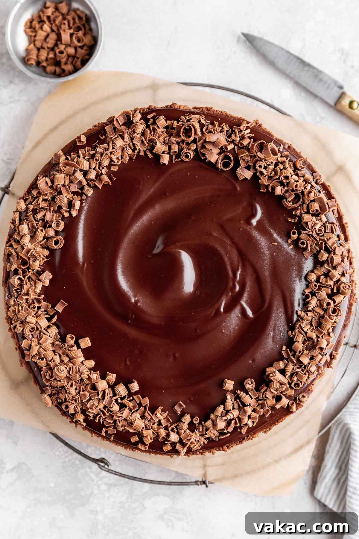 An overhead view of a gloriously decadent chocolate cheesecake, artfully garnished with a shimmering chocolate ganache and delicate chocolate shavings, highlighting its rich texture and irresistible appeal.