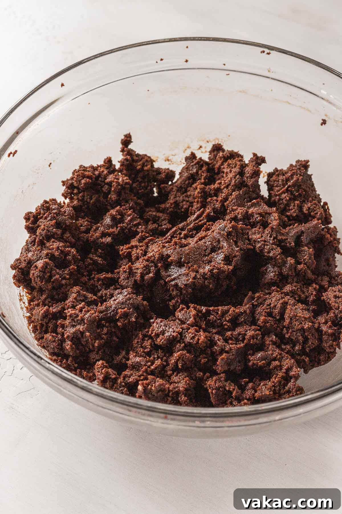 A glass mixing bowl full of crumbled cake and buttercream.