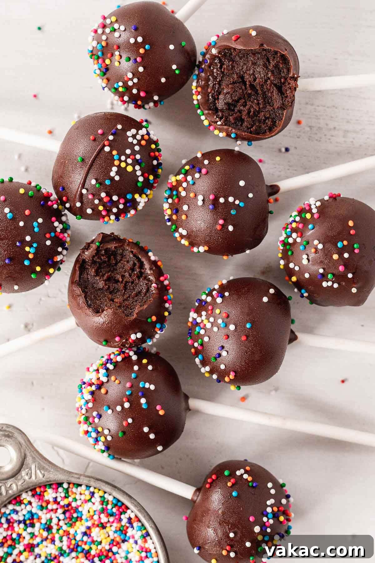 Ultimate Homemade Chocolate Cake Pops 10 An overhead view of cake pops dipped in chocolate and covered in sprinkles. Two cake pops have bites missing.