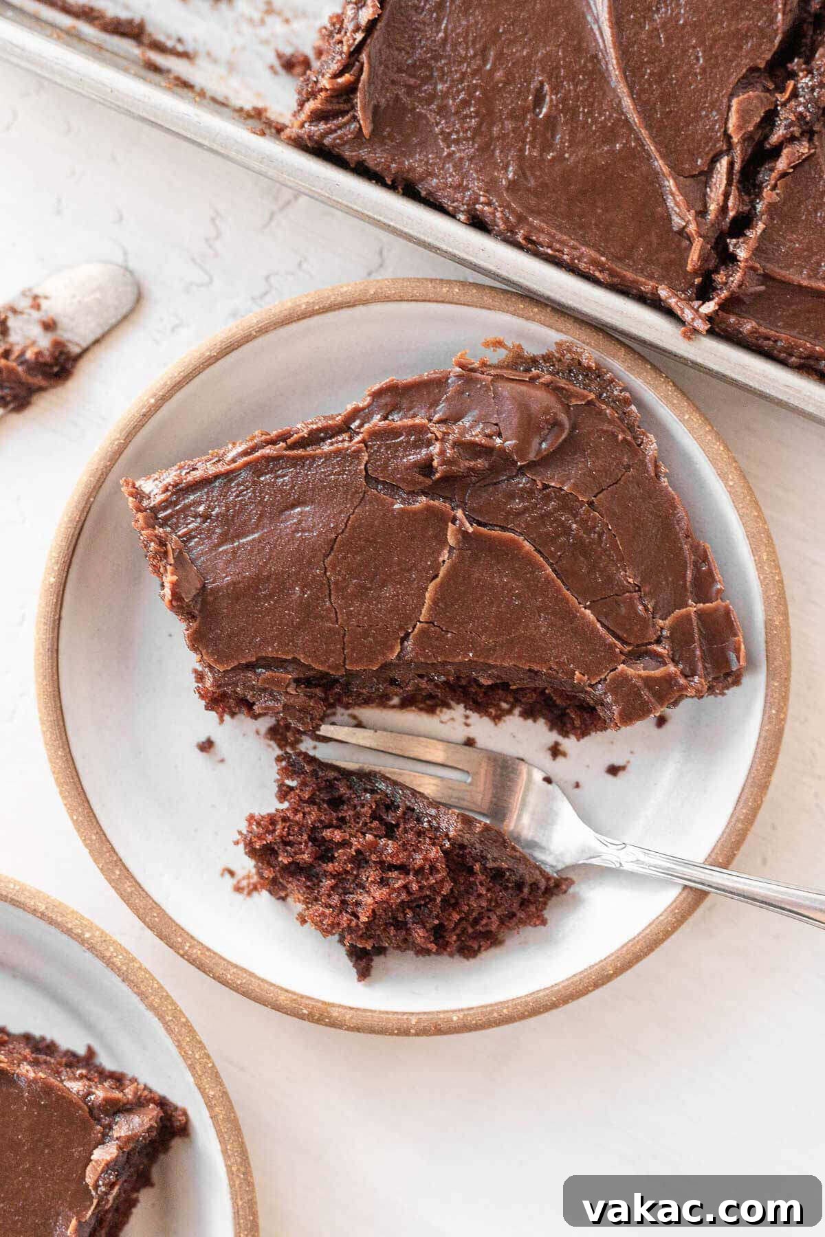 Ultimate Texas Sheet Cake 2 An overhead view of a slice of Texas sheet cake on a white plate. A bite has been cut off, revealing the moist cake texture and glossy chocolate frosting.