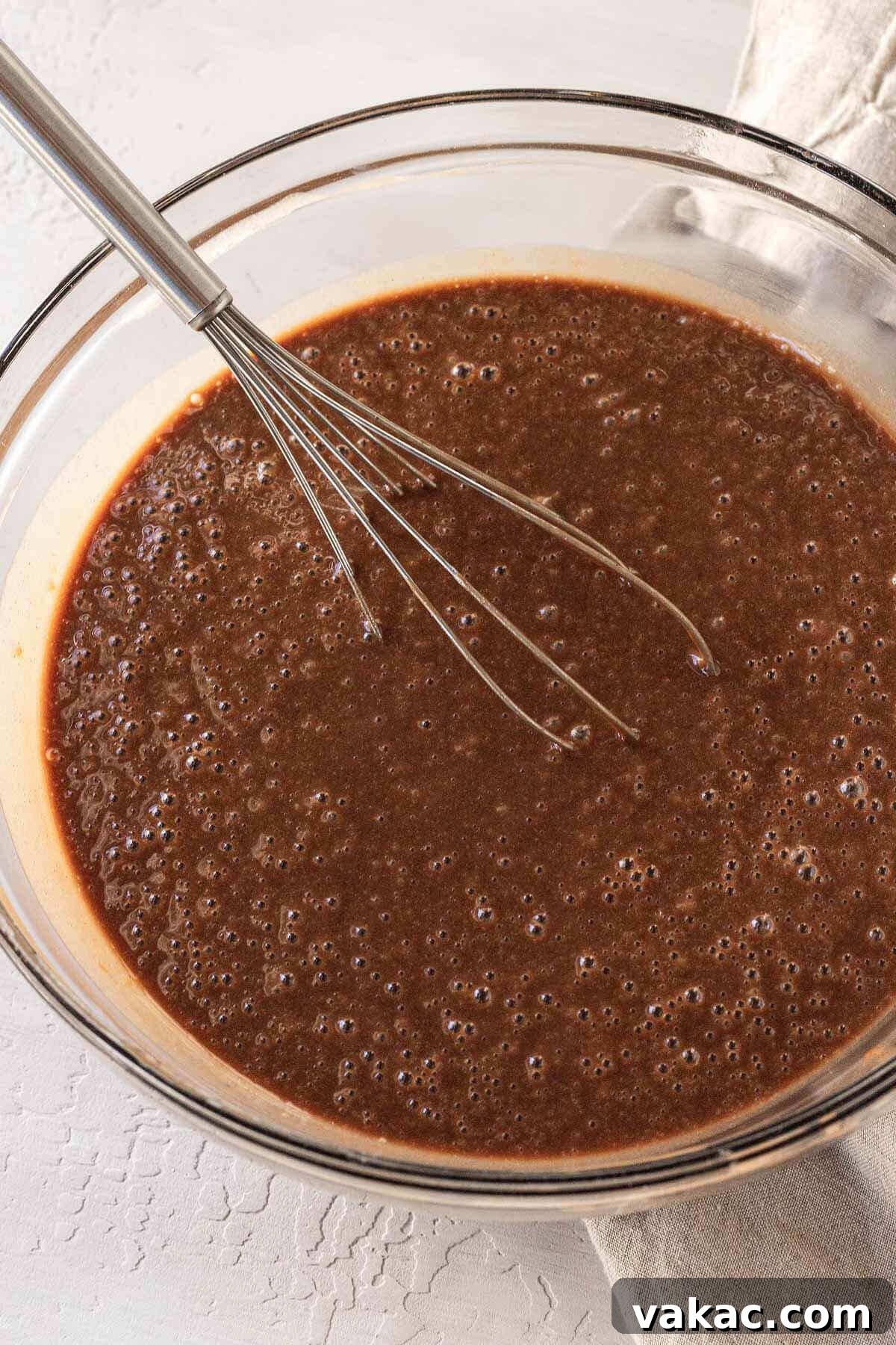Ultimate Texas Sheet Cake 6 Texas sheet cake batter, a rich, dark brown color, freshly whisked together in a glass mixing bowl, showcasing its smooth consistency before baking.