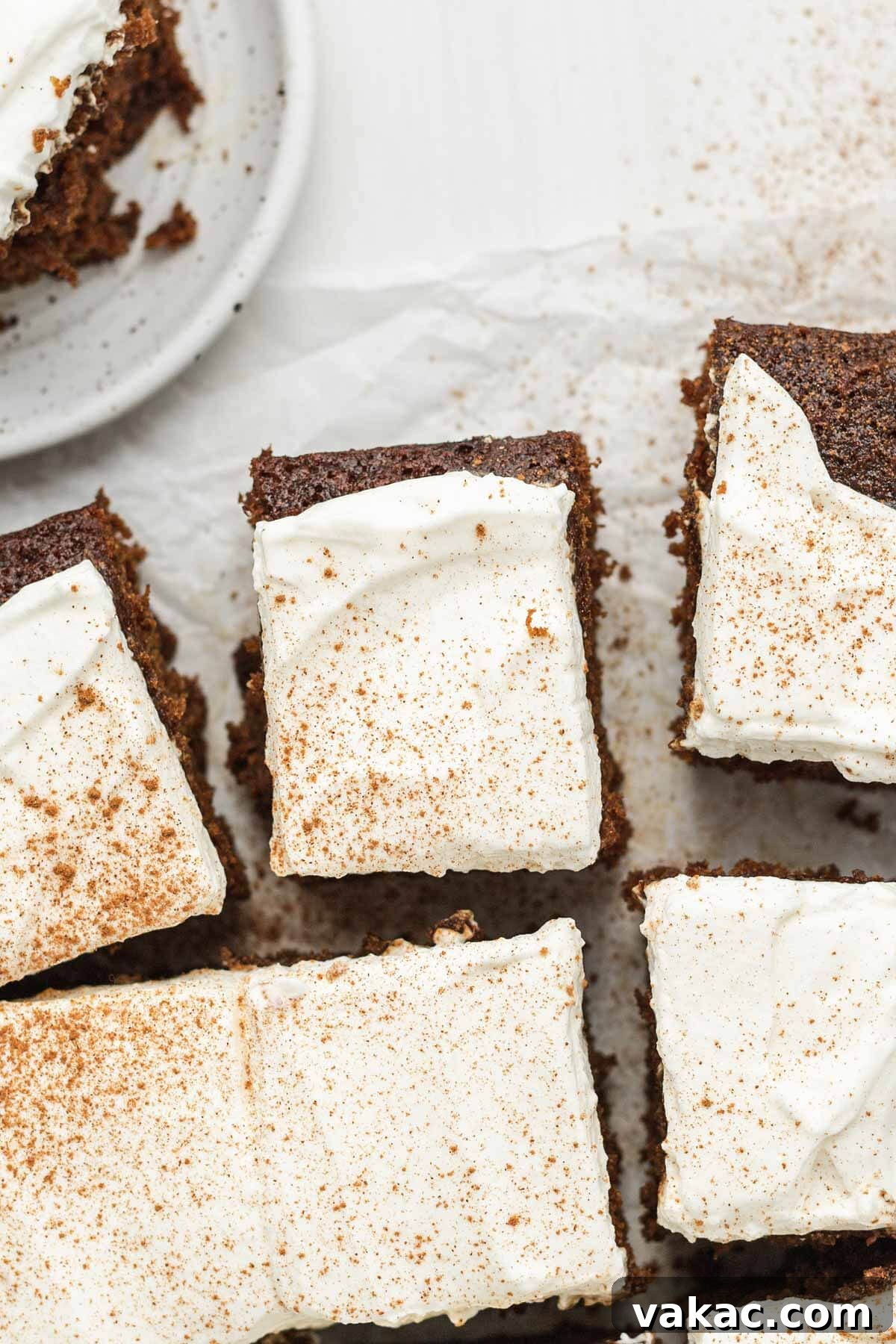 An overhead view of several slices of gingerbread cake, some with whipped cream.