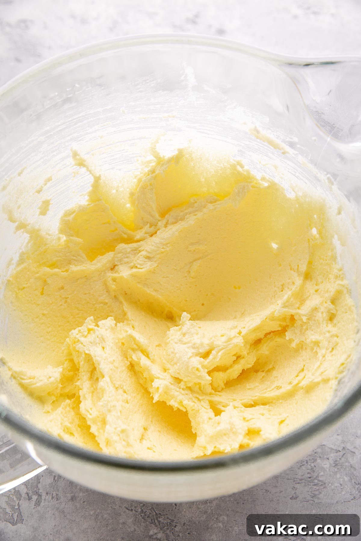 Velvet Italian Cream Indulgence 4 Softened butter, granulated sugar, and vibrant egg yolks are perfectly creamed together in a large, clear glass mixing bowl, showcasing the rich golden color and creamy texture of the base batter before the dry ingredients are added.