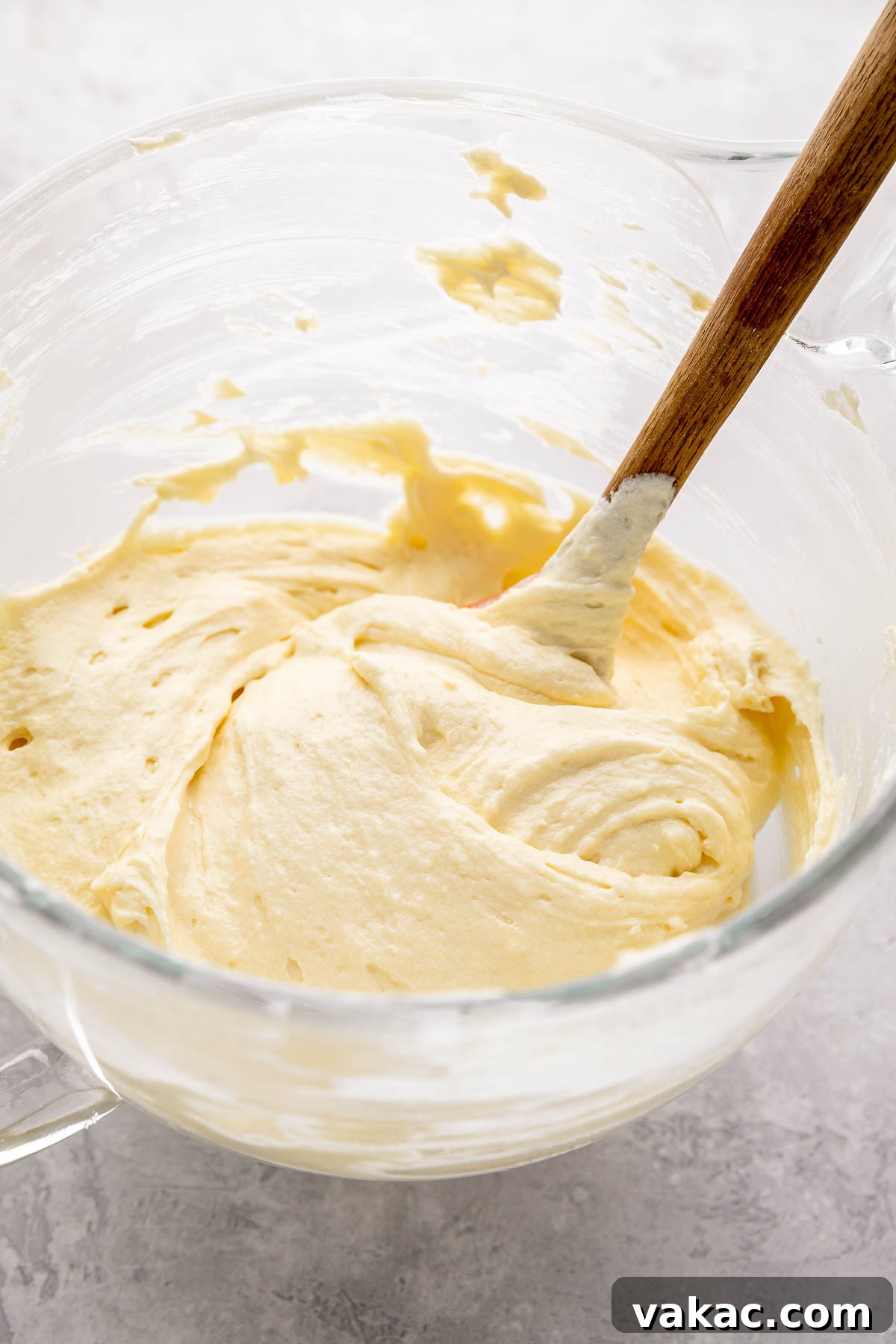 Velvet Italian Cream Indulgence 5 A smooth, light, and fluffy cake batter mixture, containing creamed butter, sugar, and egg yolks, ready for the next stage of baking, observed within a large, transparent glass mixing bowl.