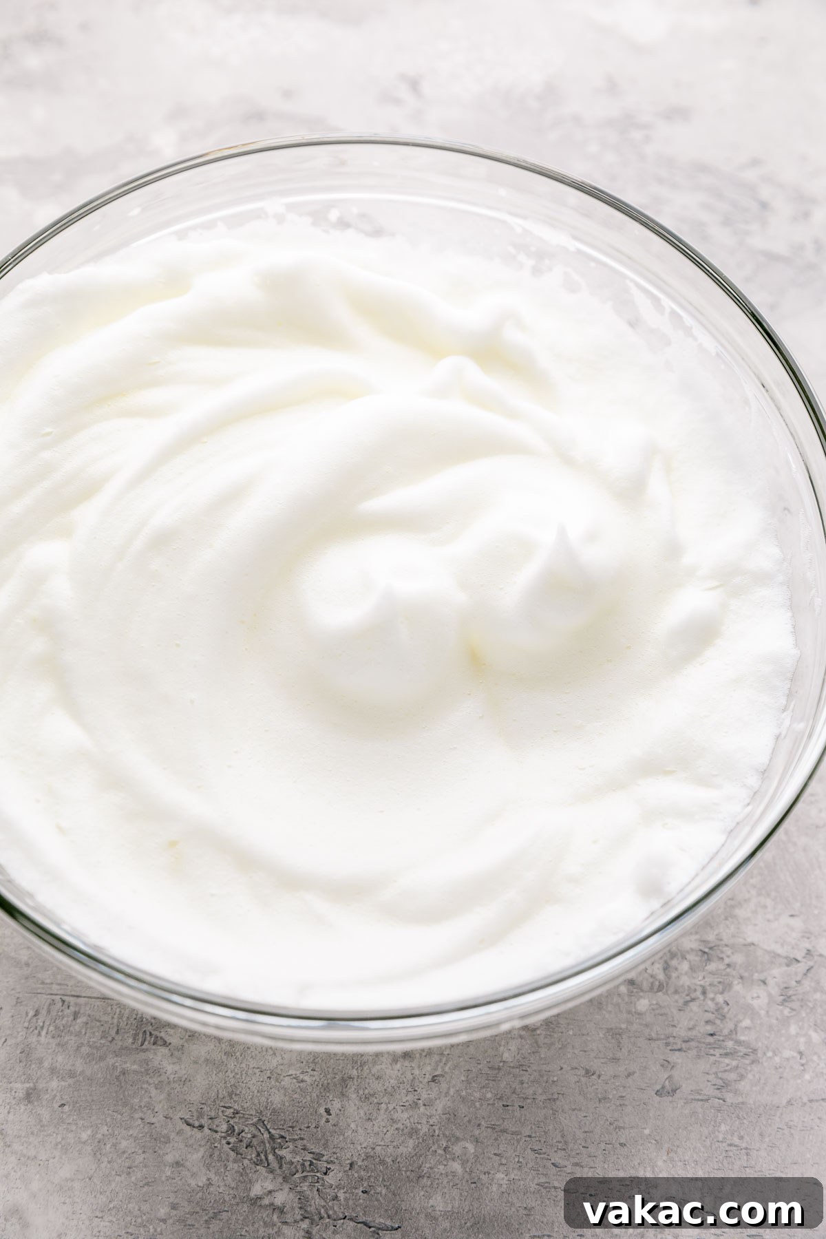Velvet Italian Cream Indulgence 6 A glass mixing bowl filled with fluffy, bright white egg whites, perfectly beaten to stiff peaks, ready to be gently folded into a cake batter to add lightness and volume.