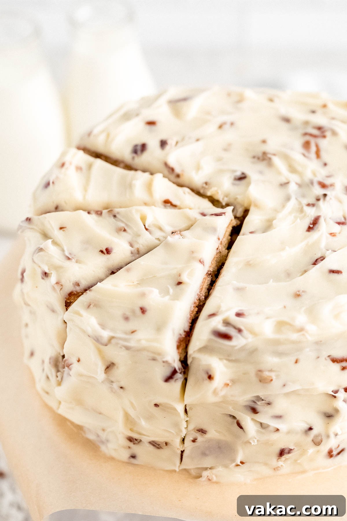 Velvet Italian Cream Indulgence 8 A freshly baked Italian Cream Cake, beautifully assembled and frosted, with a perfect slice removed to reveal its moist layers filled with pecans and coconut. The cake stands proudly on a cake stand, with two rustic milk jugs softly blurred in the background, suggesting a cozy, homemade setting.