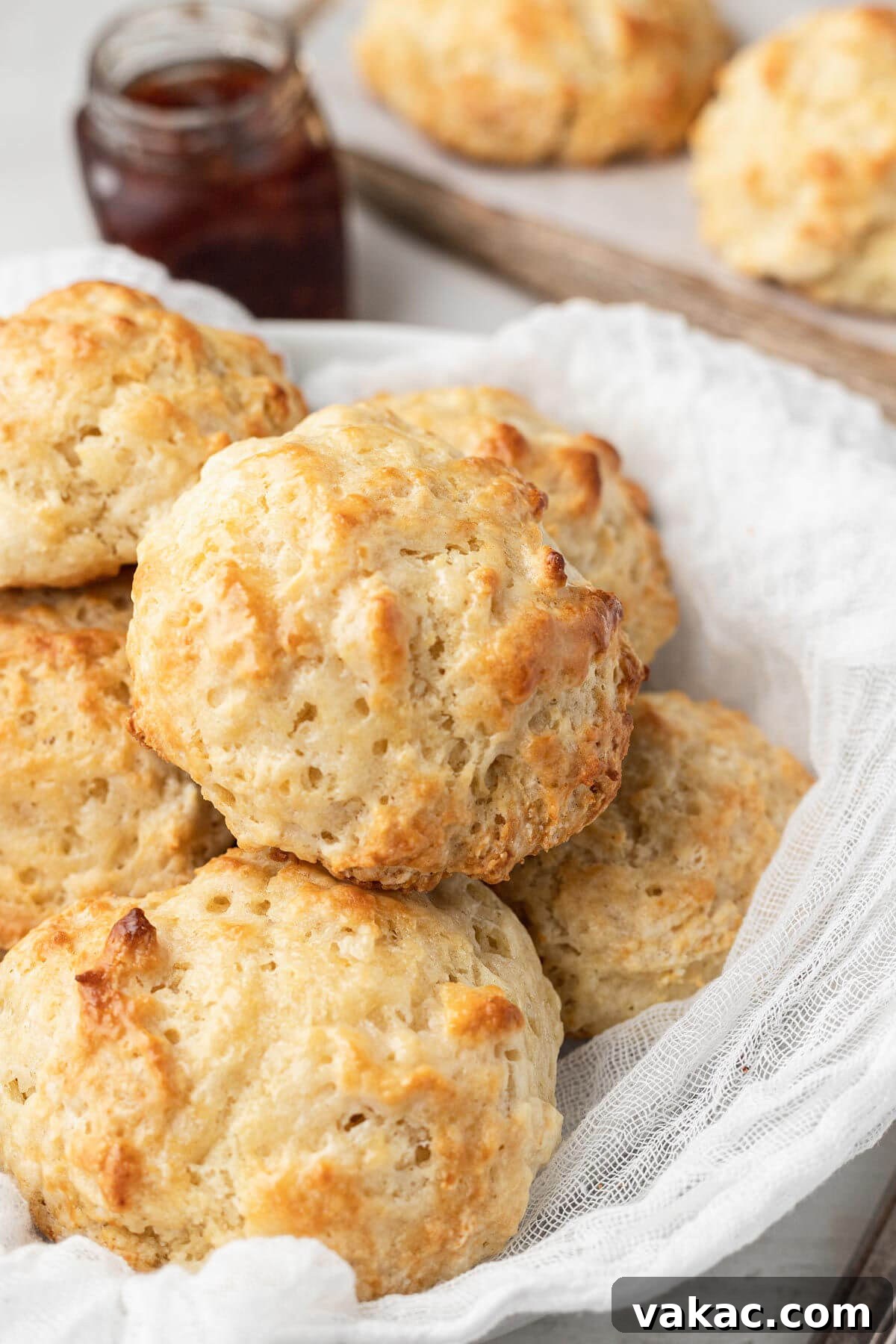 Easy Homemade Drop Biscuits 2 A pile of homemade drop biscuits in a bowl, with a jam jar in the background, suggesting a delicious breakfast or snack.