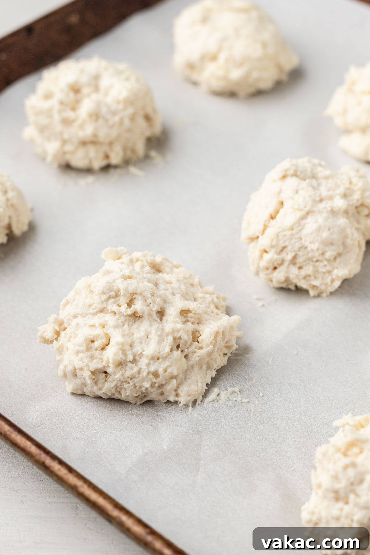 Easy Homemade Drop Biscuits 4 A parchment-lined baking sheet dotted with mounds of drop biscuit dough, perfectly spaced and ready for baking.