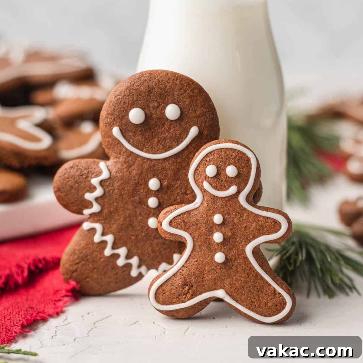 Irresistibly Soft Gingerbread 8 Two iced gingerbread cookies propped up a against a small jug of milk. More cookies rest on a plate in the background.