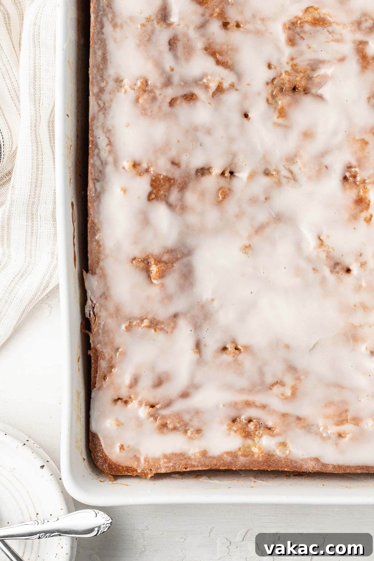 An overhead view of an iced honey bun cake in a white baking dish.