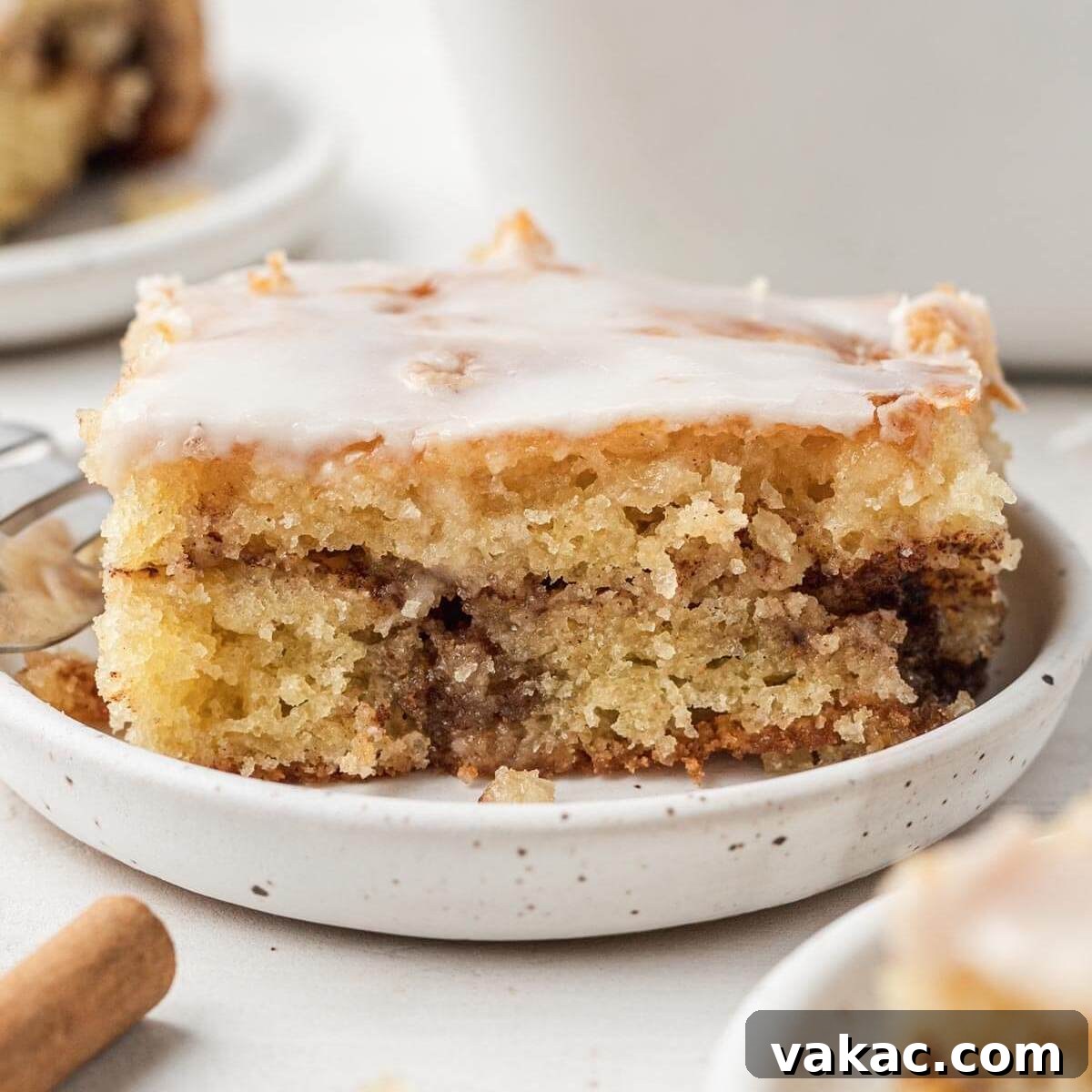 A slice of honey bun cake on a white speckled plate.