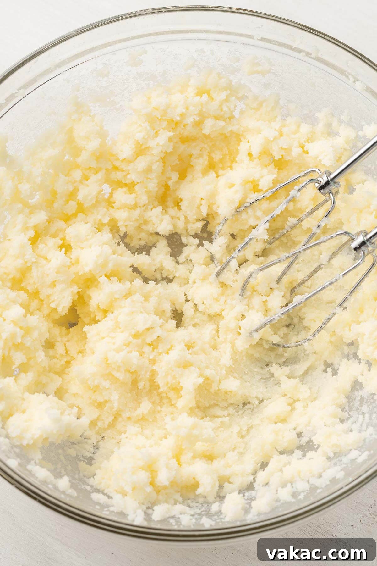 An overhead view of creamed butter and sugar in a glass mixing bowl.