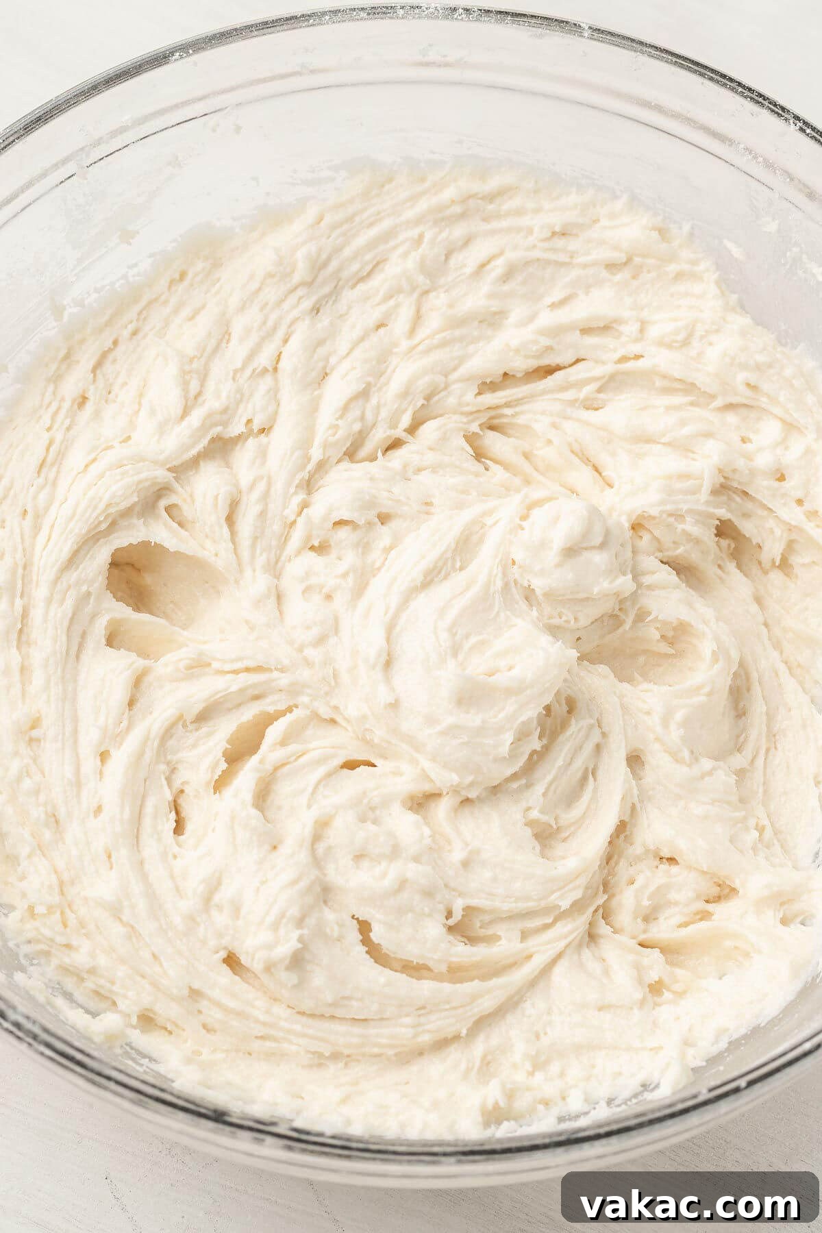 An overhead view of cake batter in a glass mixing bowl.