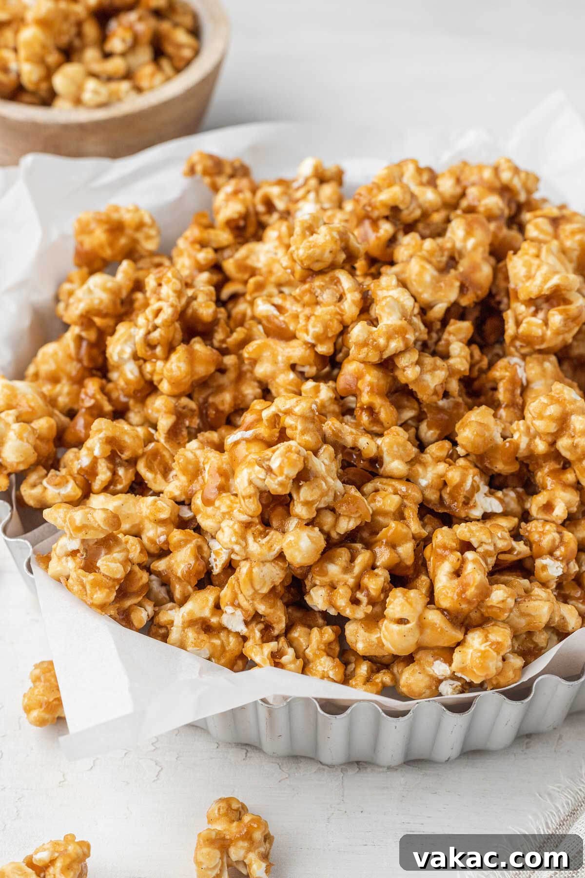 Golden Caramel Popcorn 2 A metal tart pan piled high with homemade caramel corn. A smaller dish of popcorn rests in the background.
