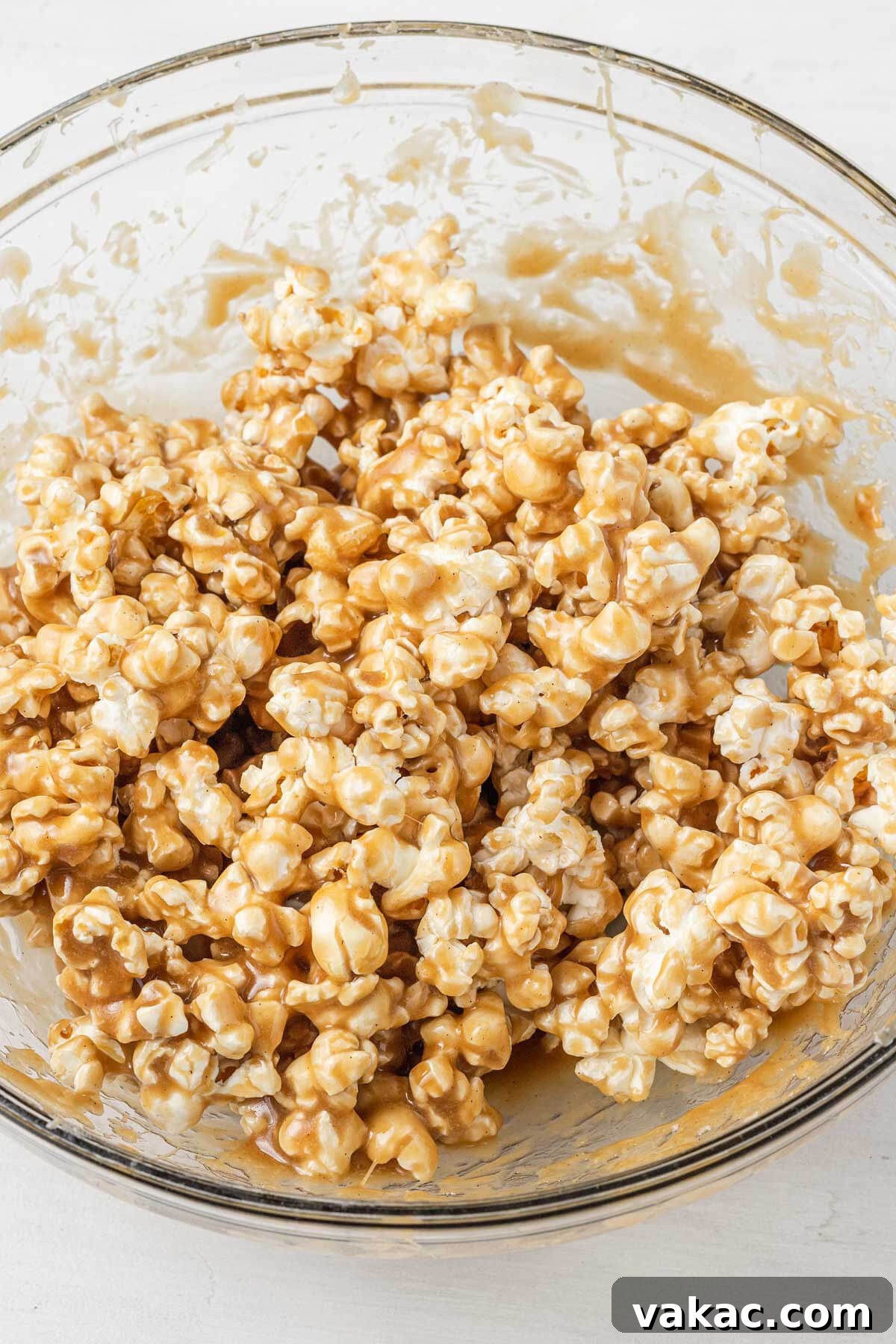 Golden Caramel Popcorn 5 Popcorn coated in caramel sauce in a large glass mixing bowl.