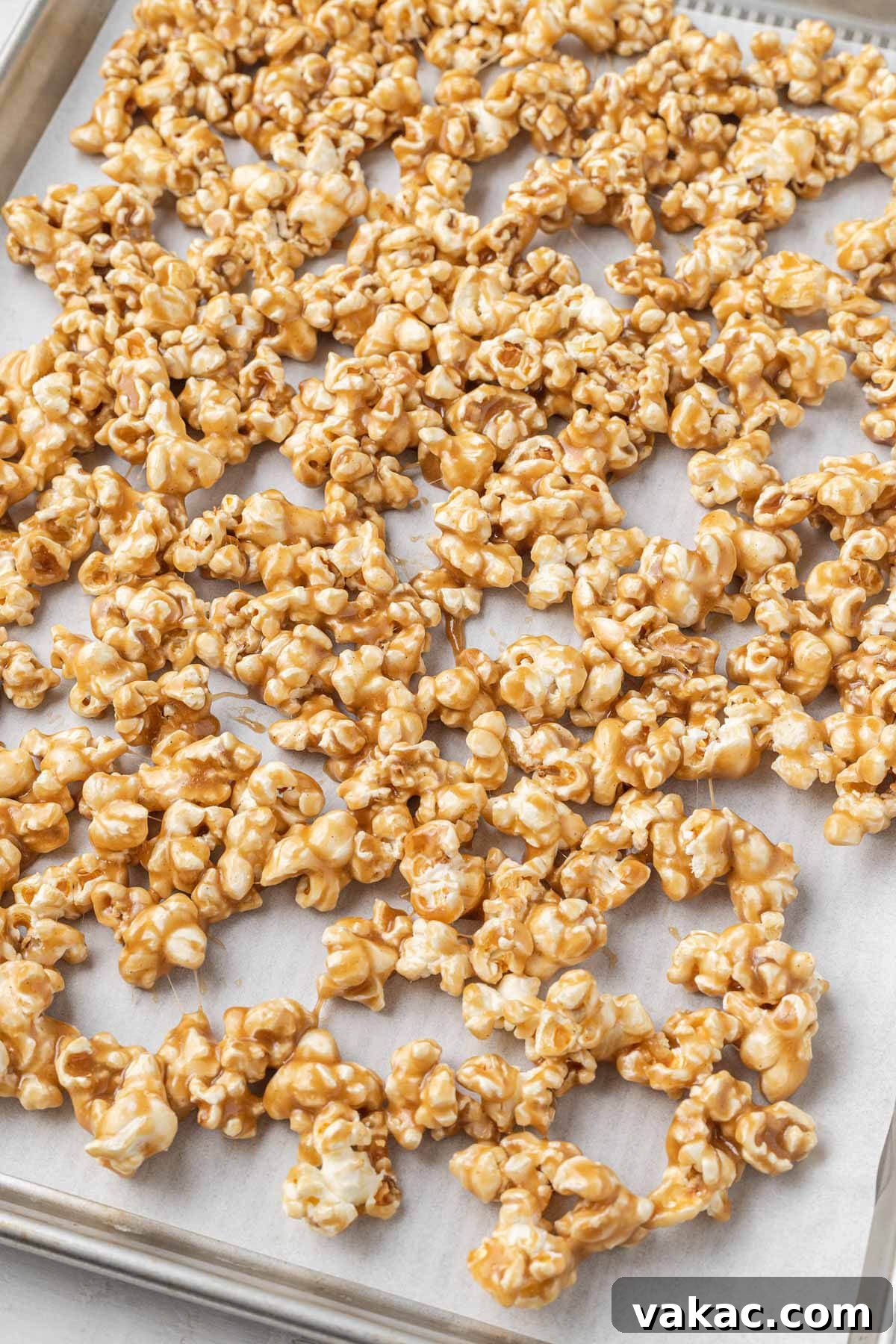 Golden Caramel Popcorn 6 Sticky caramel popcorn on a parchment-lined baking sheet.