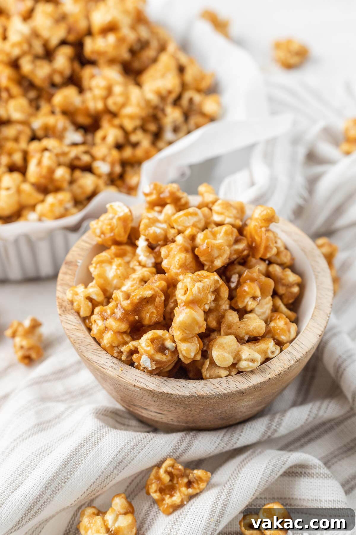 Golden Caramel Popcorn 8 A close up view of a small bowl of homemade caramel corn. A larger bowl of popcorn rests in the background.