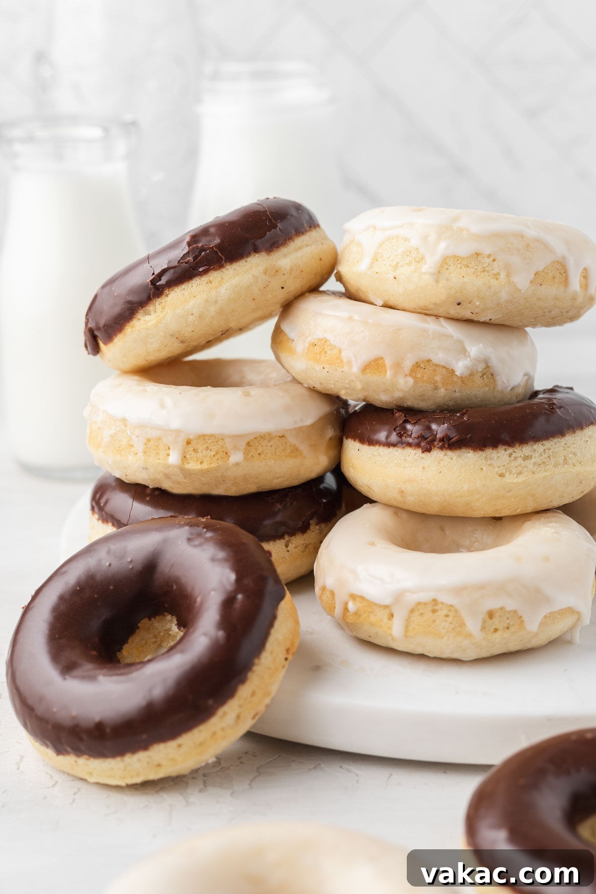 Two stacks of baked donuts with vanilla and chocolate icings. 