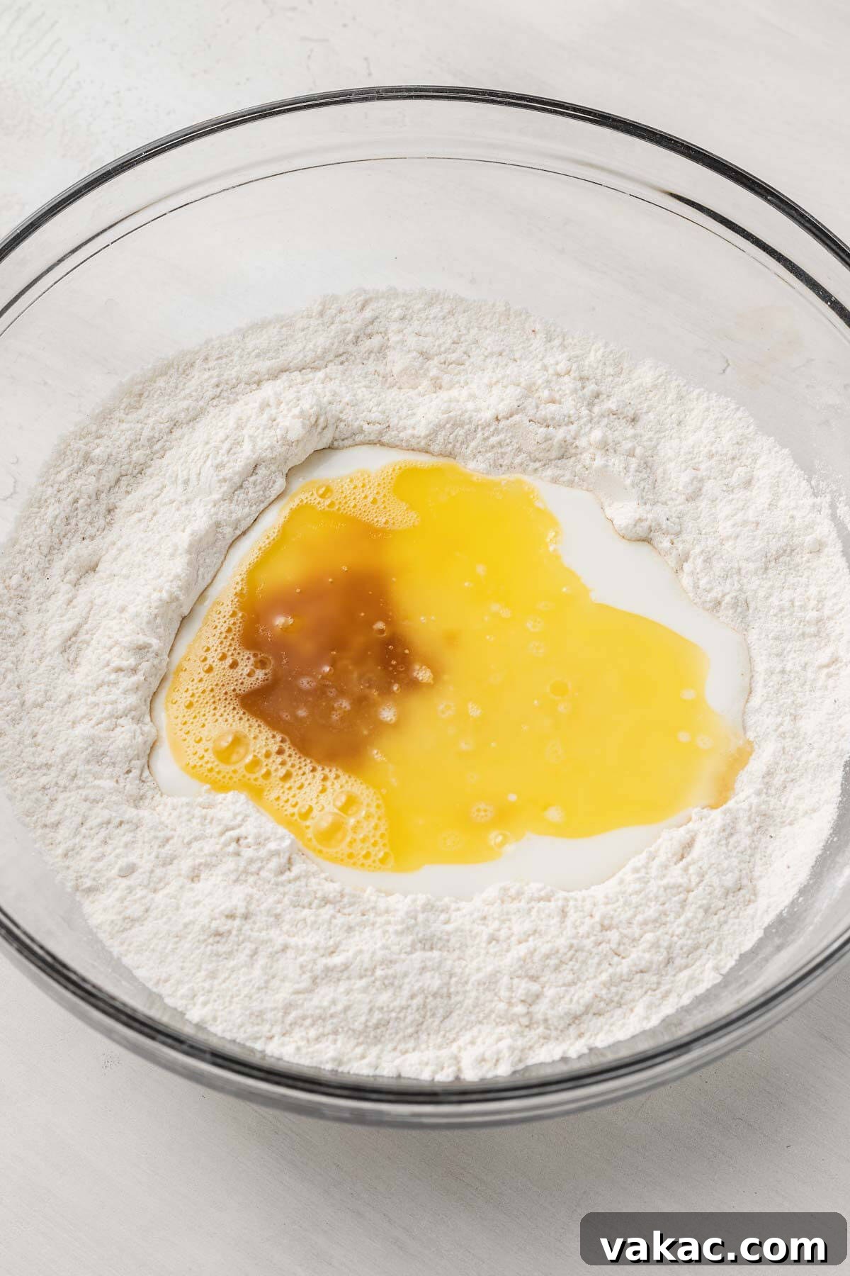 An overhead view of the dry and wet ingredients for baked donuts in a mixing bowl.