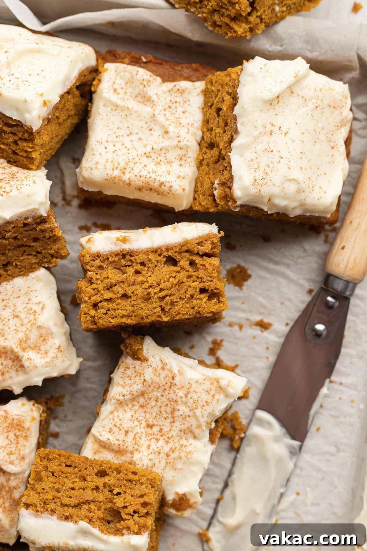 Autumn Spiced Pumpkin Bars 9 Close-up of perfectly sliced pumpkin bars with creamy frosting, artfully arranged on parchment paper, highlighting their delightful texture.
