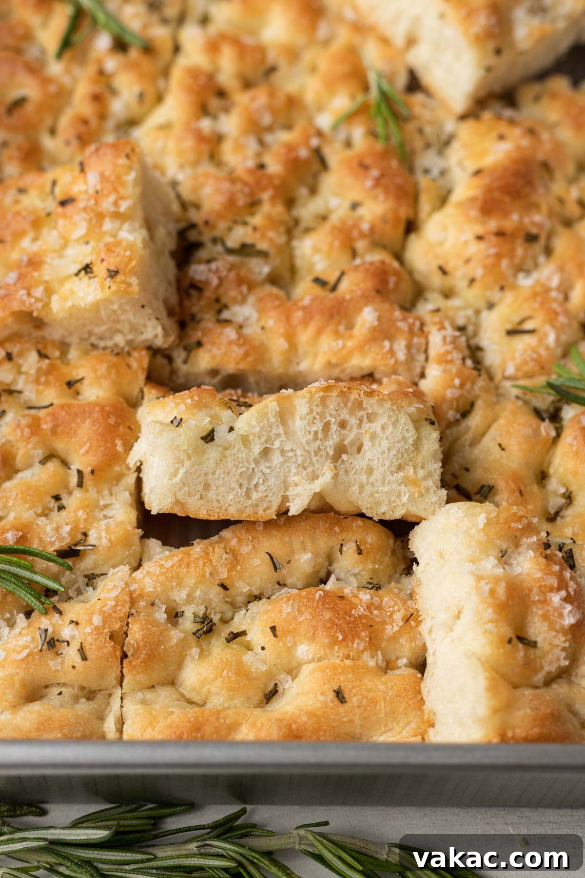 Pillowy Focaccia Perfection 2 Slices of rosemary focaccia in a metal baking pan. Some slices are turned on their sides.