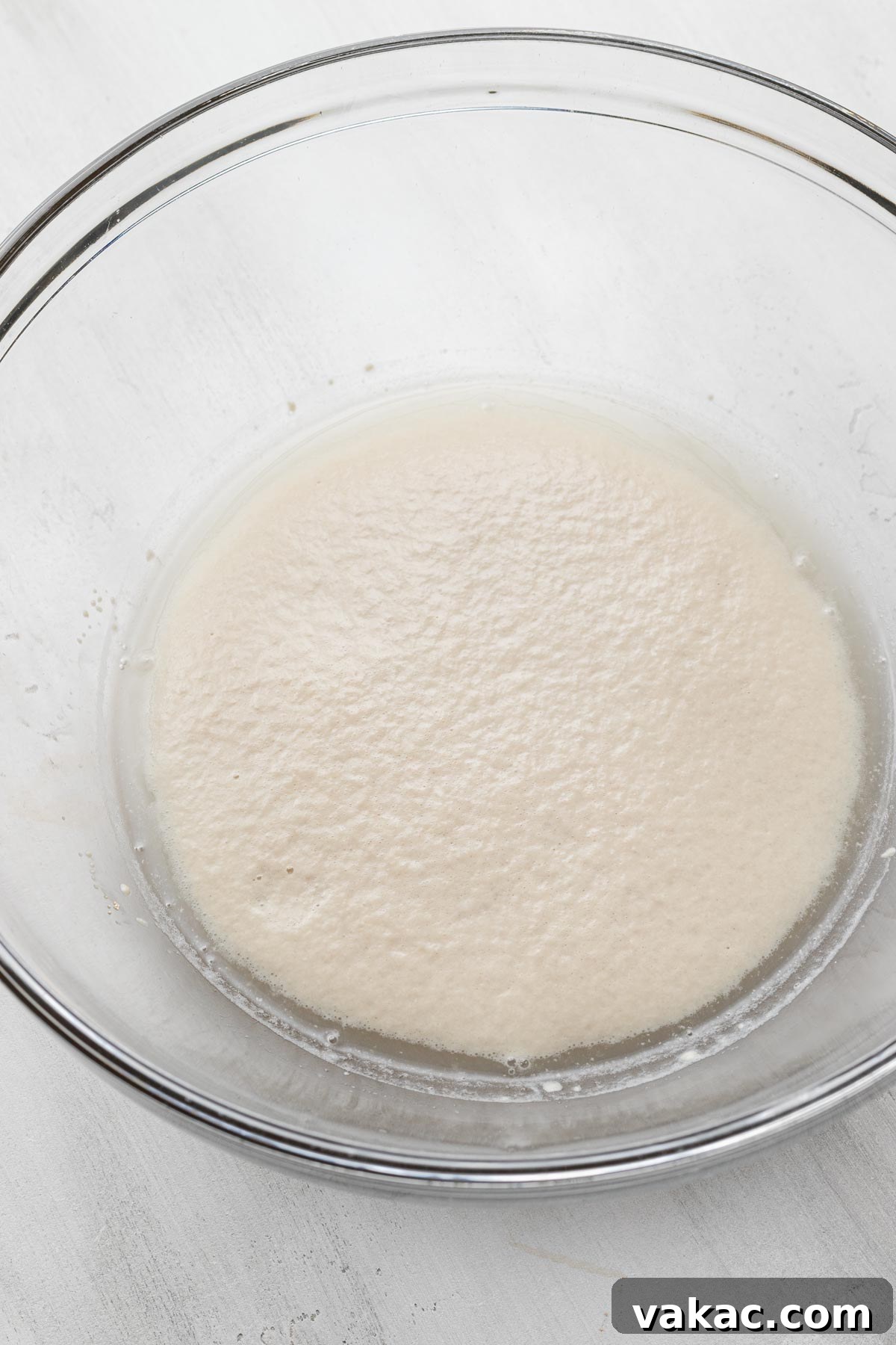 Foamy yeast mixture in a glass mixing bowl.