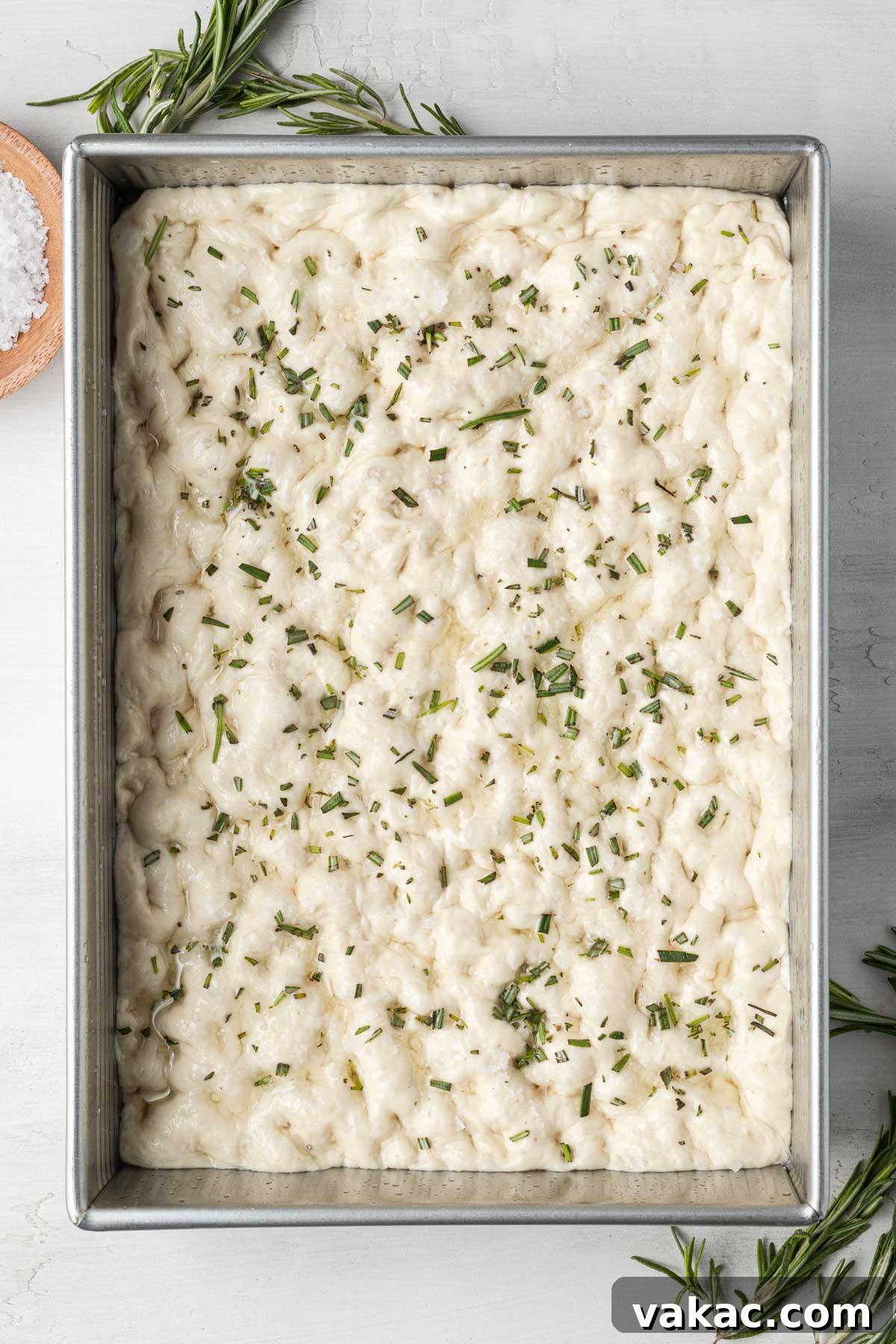 Pillowy Focaccia Perfection 5 An overhead view of raw focaccia dough in a metal baking pan.