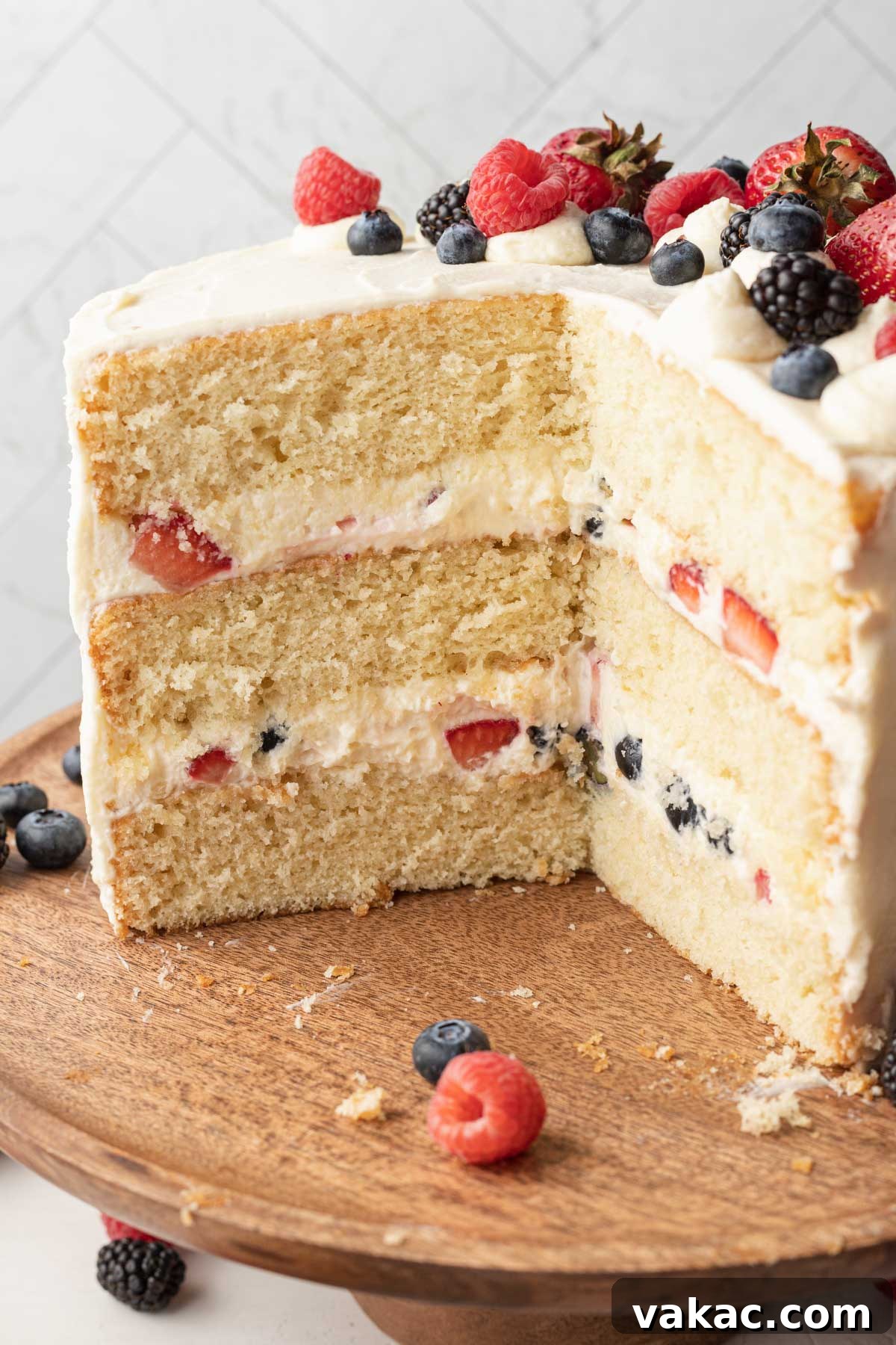 Berry Chantilly Delight 5 A perfect side view of a freshly sliced Chantilly cake, clearly displaying its multiple, distinct layers of moist vanilla cake, creamy frosting, and vibrant fresh berries.