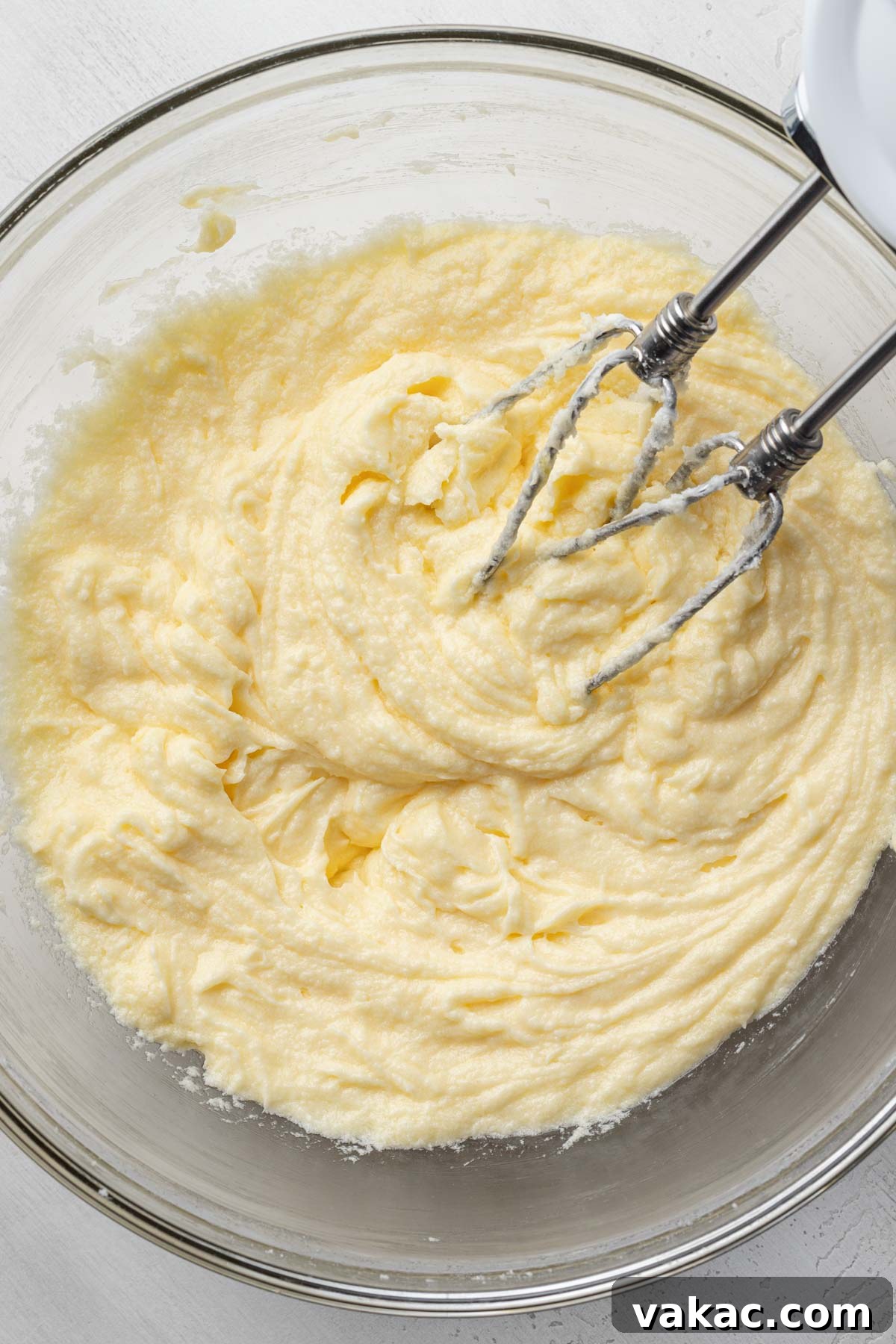 An overhead view capturing a smooth butter-egg mixture expertly blended in a clear glass mixing bowl, a key step in preparing the Chantilly cake batter.