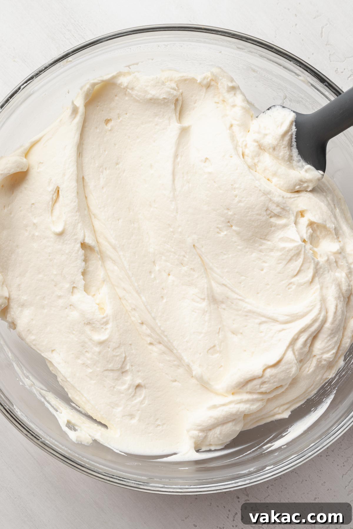 An overhead shot showcasing the smooth, fluffy texture of freshly prepared Chantilly cake frosting, glistening in a mixing bowl and ready for assembly.