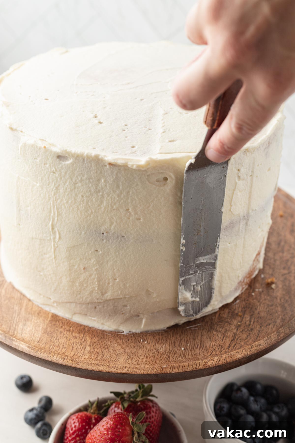 A detailed process shot illustrating how to apply the creamy frosting to the exterior of a multi-layered Chantilly cake, ensuring a smooth finish.