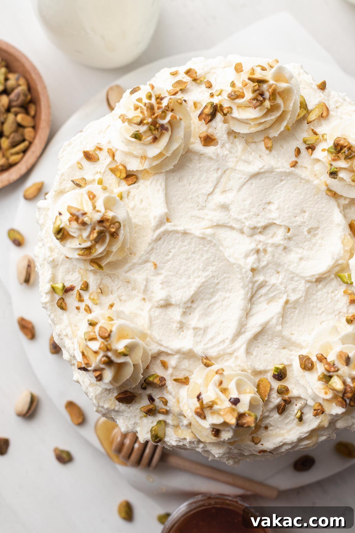 Velvet Pistachio Indulgence 2 An overhead view of a frosted pistachio cake, with pistachios and honey on the side.