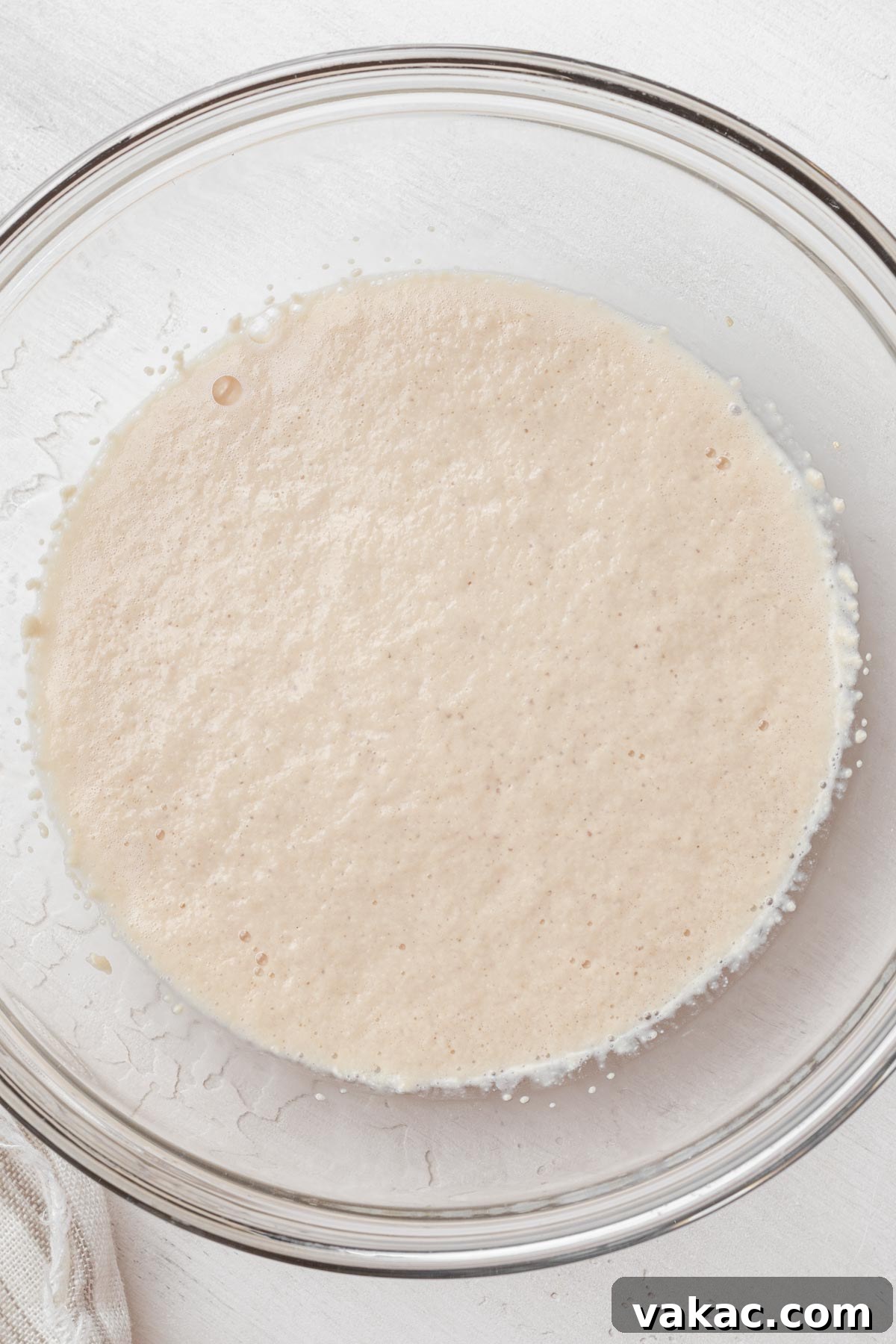 Warm Caramel Pull-Apart Delight 4 Overhead view of active dry yeast proofing in a glass mixing bowl, showing a foamy layer on top.