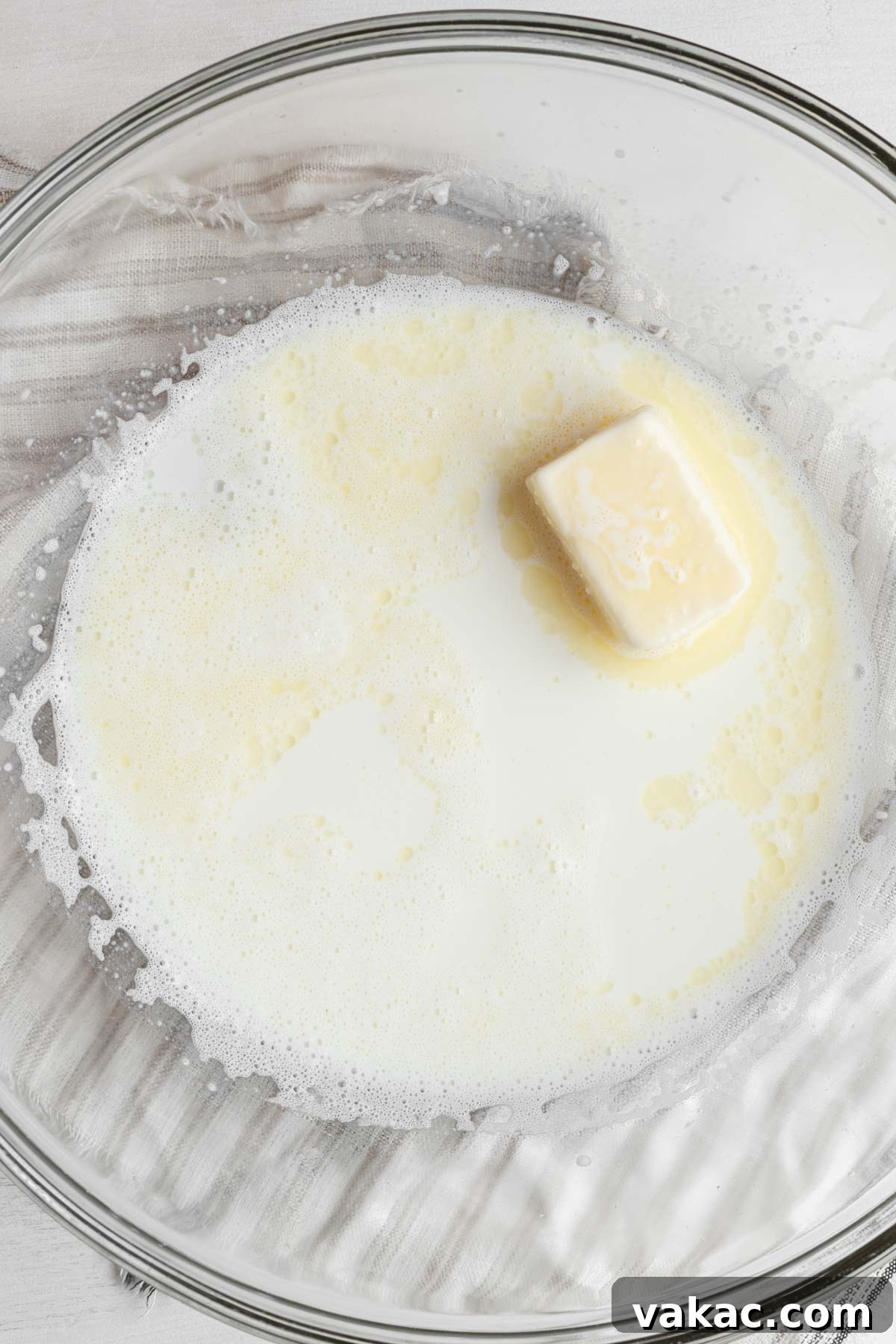 Overhead view of sugar, butter, salt, and scalded milk in a large mixing bowl, ready for dough preparation.
