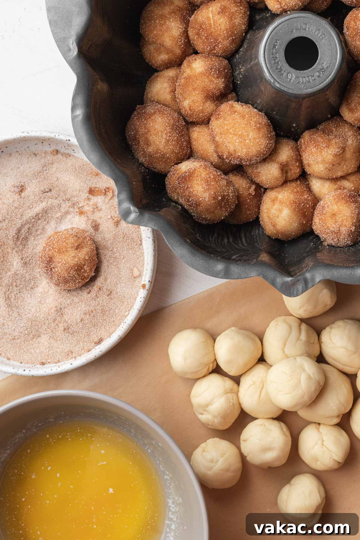 An assembly shot showing how small balls of monkey bread dough are coated and placed in a bundt pan.