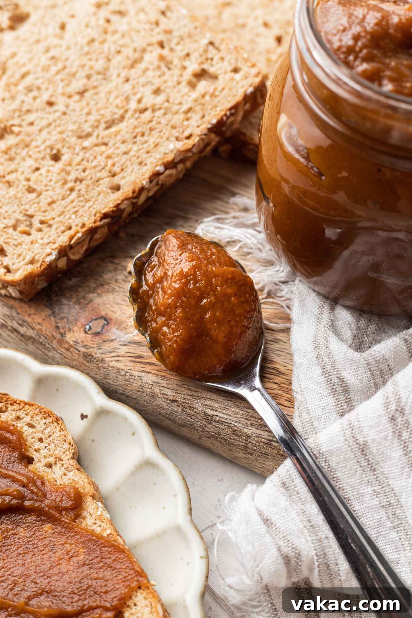 Golden Pumpkin Butter 6 A spoonful of pumpkin butter next to a jar and bread slices.