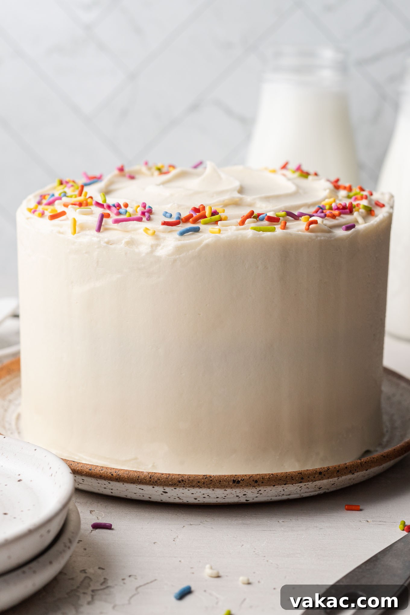 Petite Vanilla Perfection 2 A beautifully frosted 6-inch vanilla cake on a speckled white plate, ready to be served.