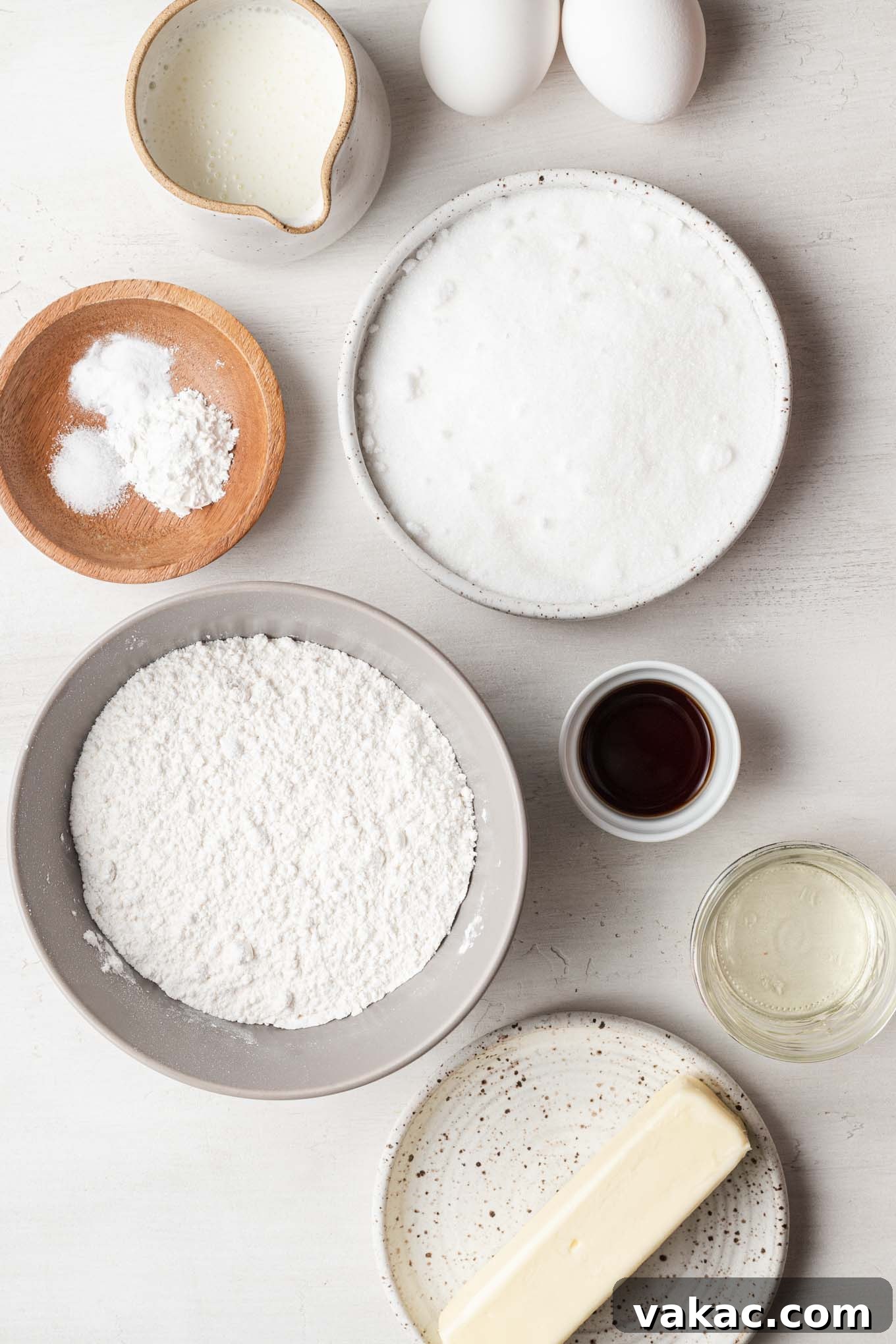 Petite Vanilla Perfection 3 An overhead view of all the essential ingredients laid out for baking a small vanilla cake from scratch.
