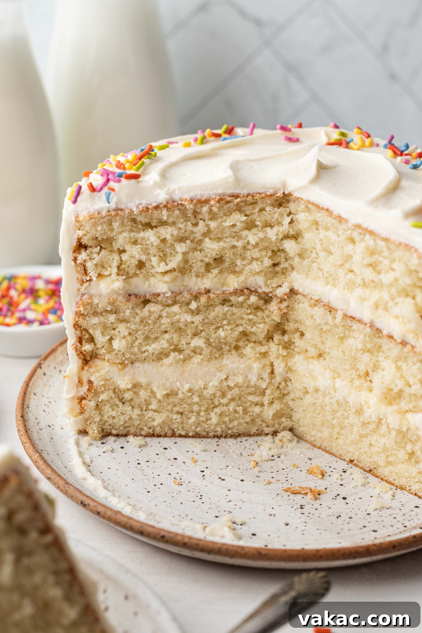 Petite Vanilla Perfection 9 A beautiful side view of a small vanilla cake, with slices already removed, perfectly showcasing its delicate layers of cake and frosting.