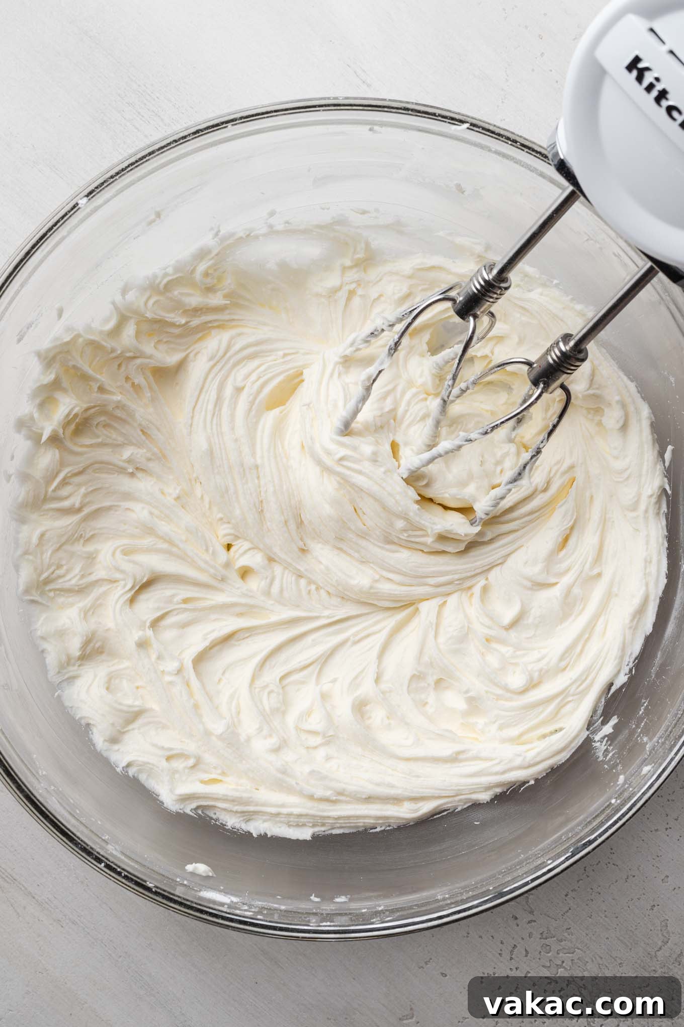 An overhead view of creamed butter and sugar in a glass mixing bowl with a hand mixer.