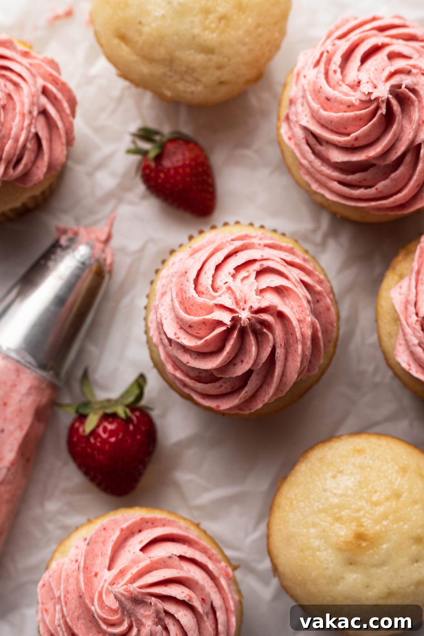 Velvet Strawberry Frosting 5 An overhead view of strawberry frosted cupcakes, fresh berries, and a piping bag.
