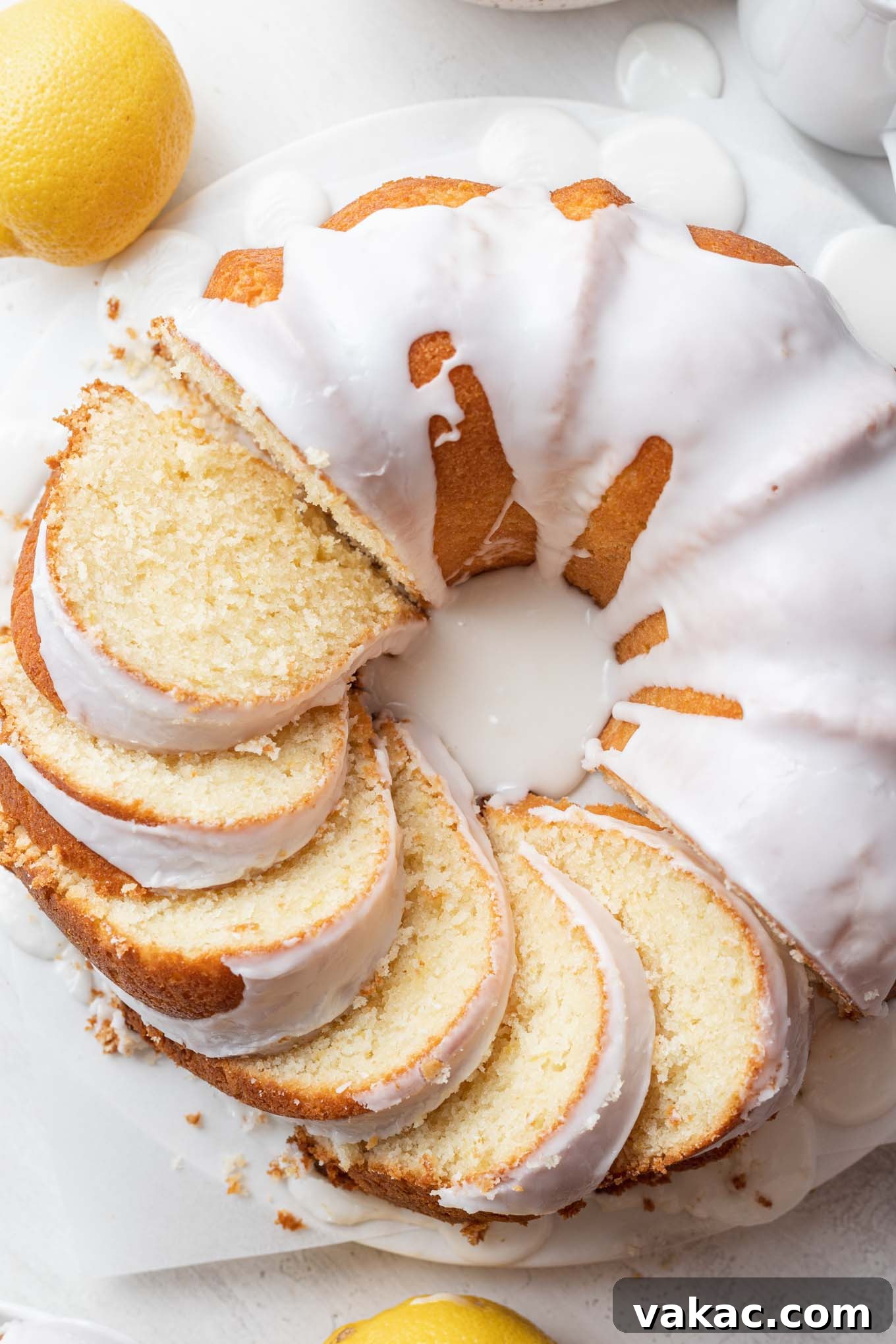 Sunshine Lemon Pound Cake 8 An overhead view of a lemon sour cream pound cake. Half the cake has been sliced, and the slices are laying on their sides.