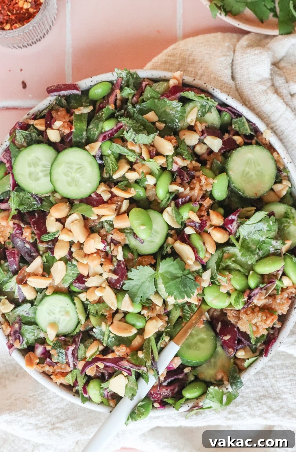The vibrant Thai Crispy Rice Salad mixed in a bowl, with a gold spoon resting inside, showcasing its inviting textures.