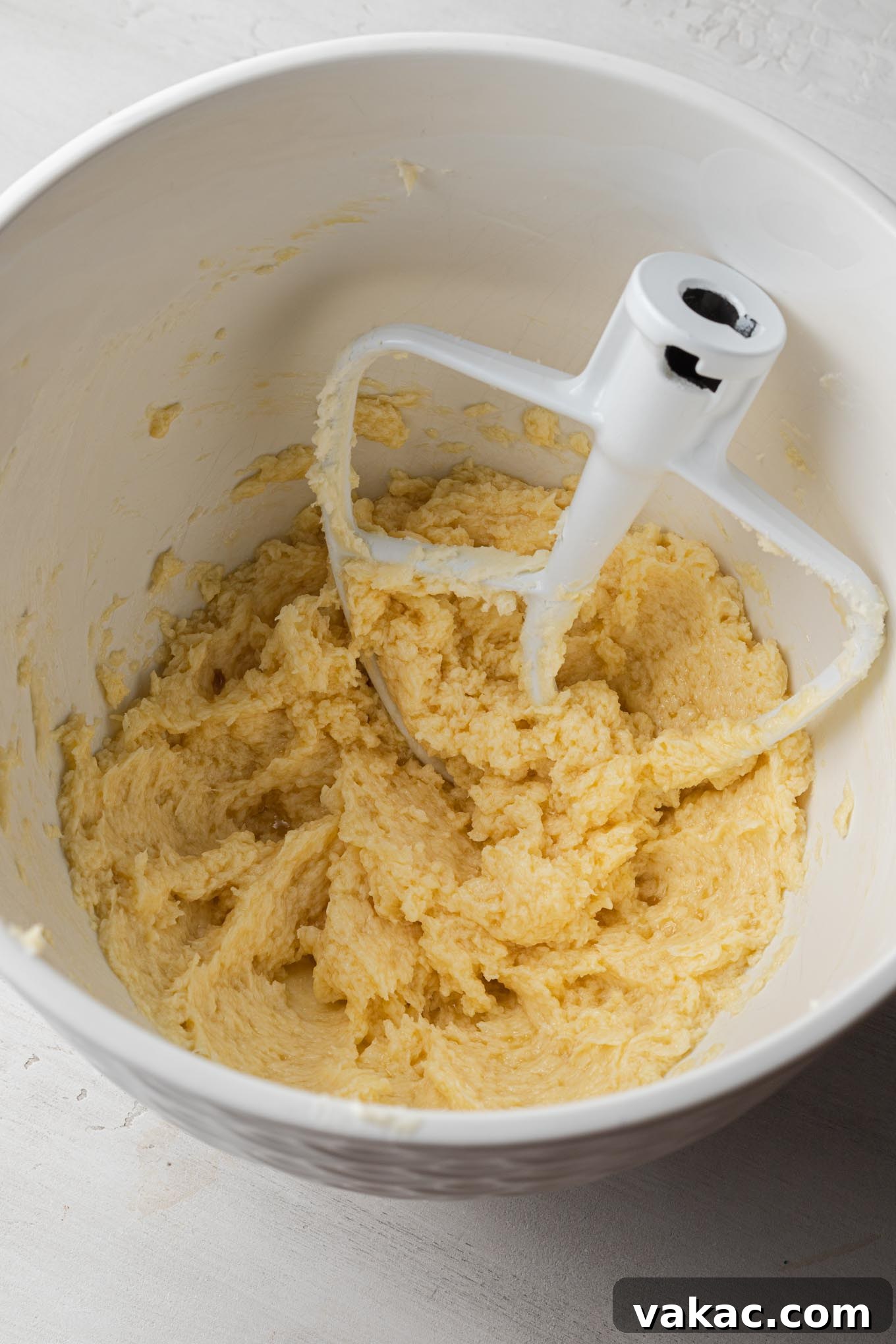 Buttery Spritz Cookies 4 Creamed butter and sugar in a white mixing bowl, with a paddle attachment for a stand mixer.