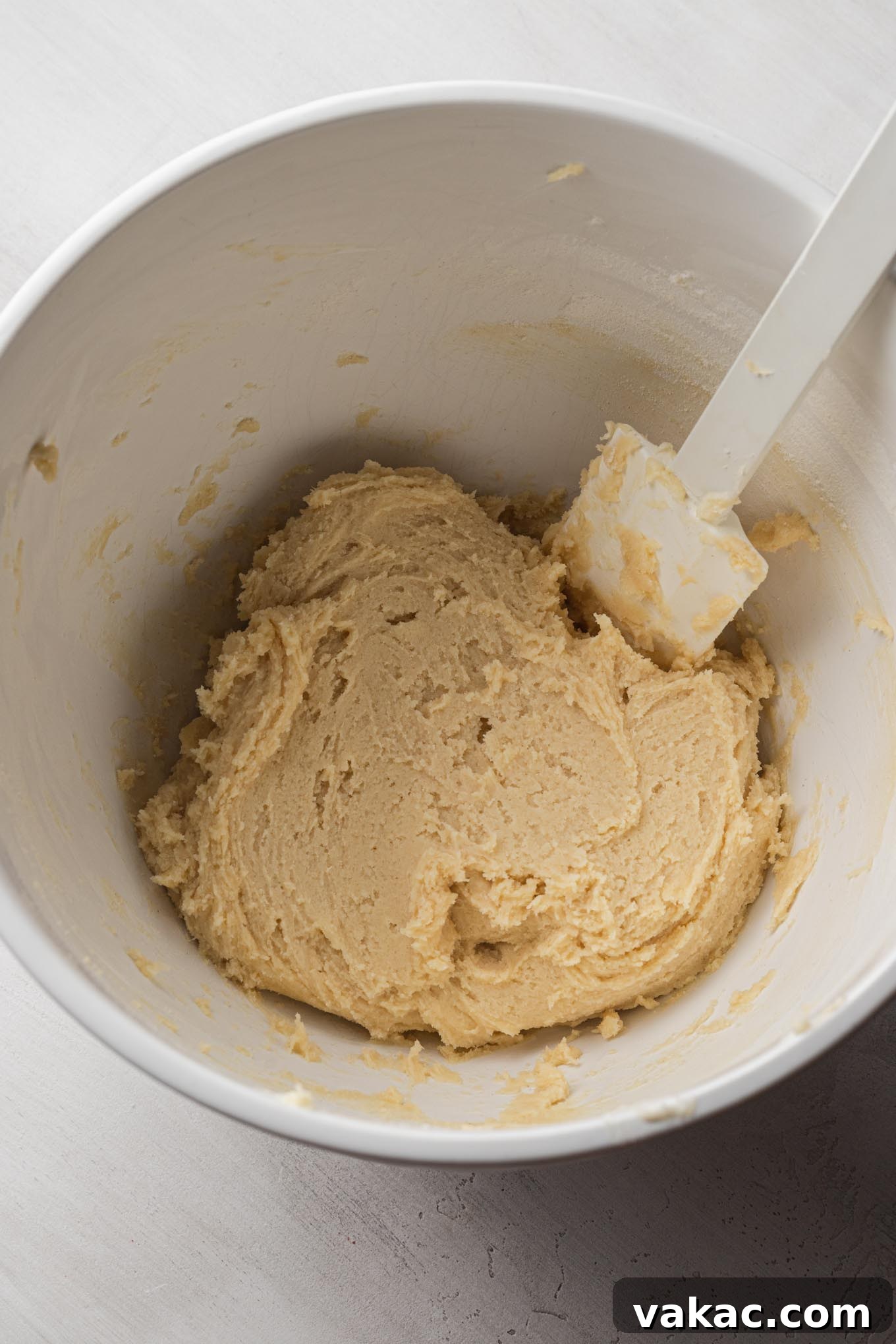 Buttery Spritz Cookies 5 Spritz cookie dough in a white mixing bowl with a rubber spatula.