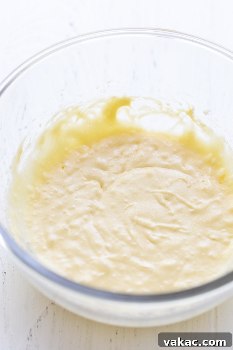 A glass mixing bowl holding the wet ingredients for the cake.