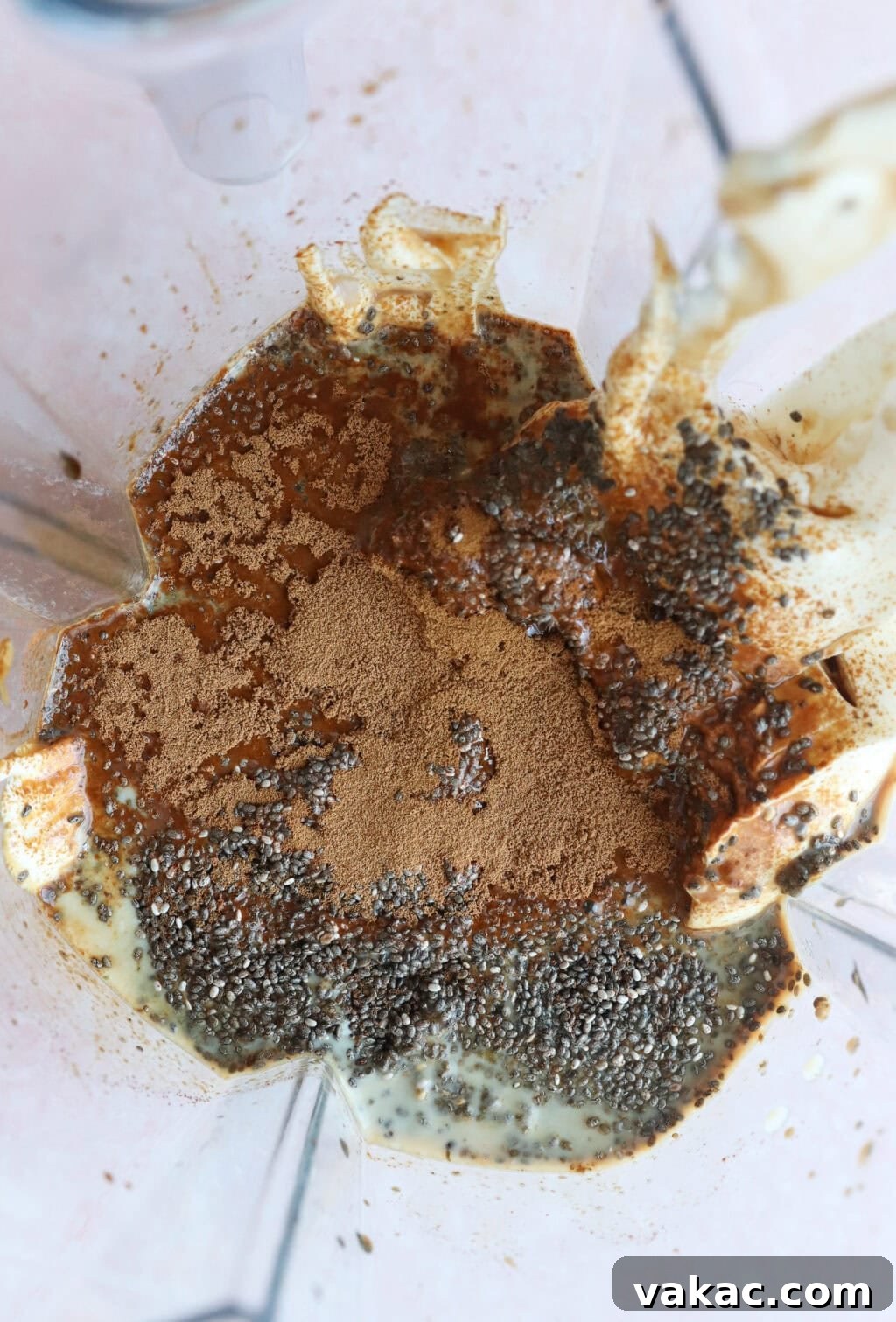 Dreamy Protein Tiramisu Chia Pudding with Yogurt 5 A close-up view from above of a blender containing chia seeds, cinnamon, a creamy liquid, and possibly protein powder, before blending.