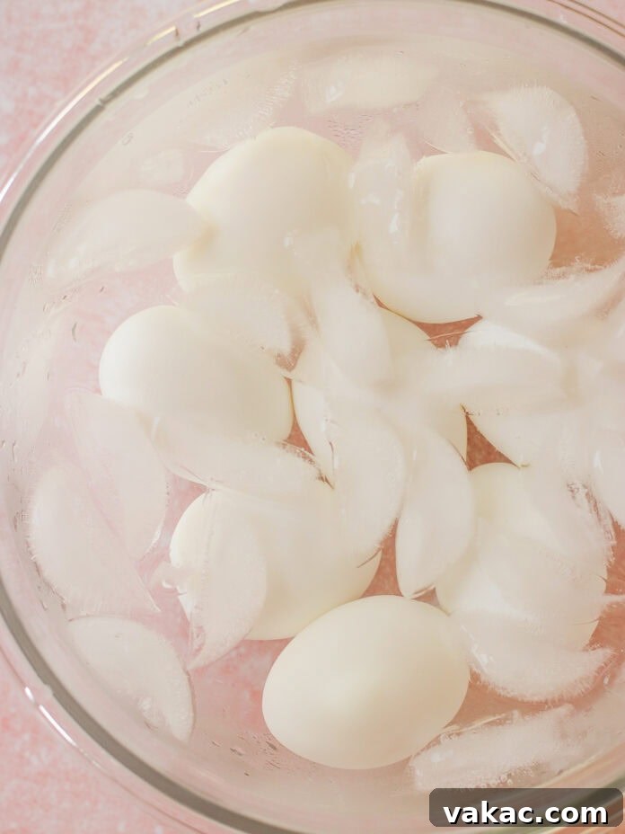 Creamy High Protein Cottage Cheese Egg Salad No Mayo 4 A glass bowl filled with hard-boiled eggs and ice cubes submerged in water, creating an ice bath.