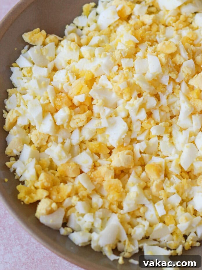 Creamy High Protein Cottage Cheese Egg Salad No Mayo 6 A close-up of a bowl filled with finely chopped hard-boiled eggs, showing a mix of yellow yolks and white egg whites.